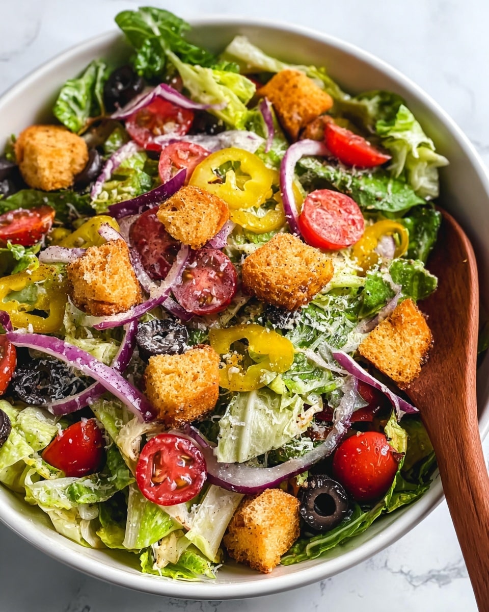 A large white bowl filled with a colorful salad sits on a white marbled surface. The salad has three main layers: fresh green lettuce leaves forming the base, topped with slices of red tomatoes, black olives, purple onion rings, and yellow pepperoncini peppers scattered around. The top layer is golden-brown croutons sprinkled evenly, with a light dusting of grated cheese over everything. A woman's hands hold wooden salad spoons on each side of the bowl, ready to toss the salad. Nearby is a clear glass jar with creamy yellow dressing inside. Photo taken with an iphone --ar 4:5 --v 7