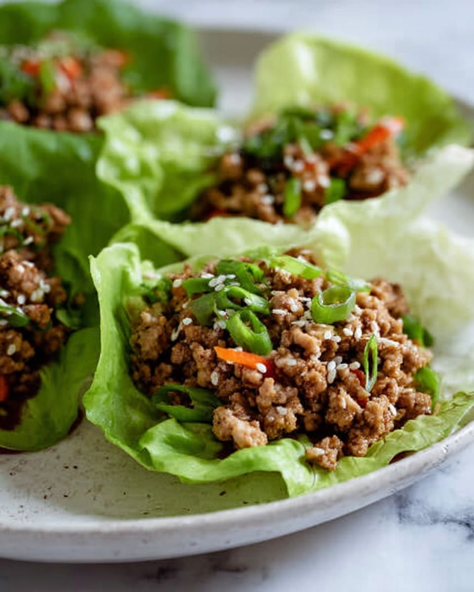 The image shows three lettuce cups placed on a white plate with a white marbled surface background. Each lettuce cup has a base layer of light green, crisp lettuce leaves shaped to hold the filling. On top, there is a layer of ground meat mixed with small pieces of orange carrot and garnished with sesame seeds scattered over the top. Fresh sliced green onions are sprinkled over the meat, adding a fresh green contrast. The food looks fresh and colorful, showing texture from the crunchy lettuce and savory meat mixture, photo taken with an iphone --ar 4:5 --v 7