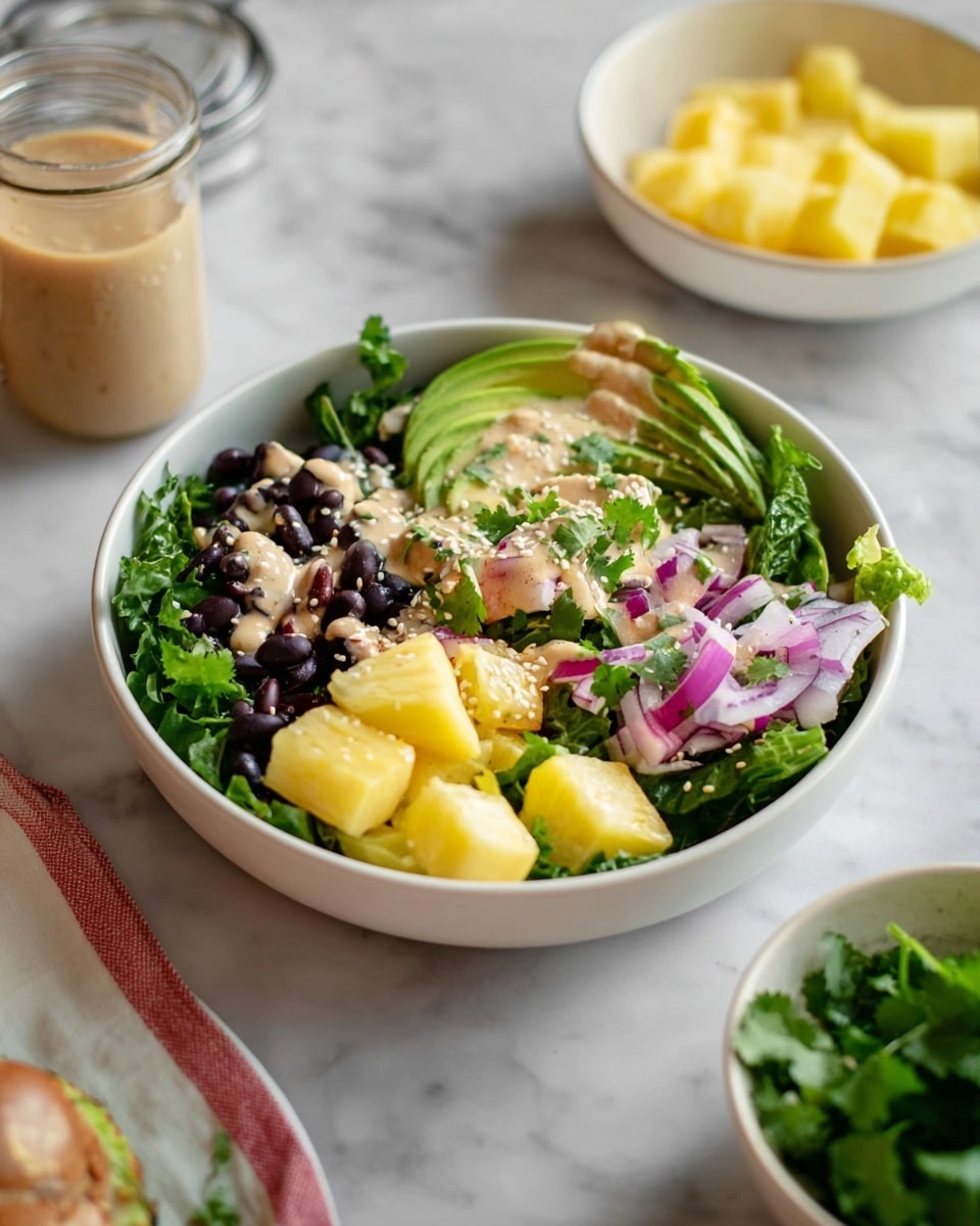 A white bowl filled with a fresh salad sits on a white marbled surface. The salad has multiple layers: the base is made of dark green leafy lettuce, topped with black beans scattered around. Over the black beans, there are bright yellow pineapple chunks and slices of light green avocado fanned out on one side. Thin slices of purple onion are spread over the salad, along with finely chopped green cilantro. A light tan creamy dressing is drizzled over the top, sprinkled with light brown sesame seeds. Nearby, there is a white bowl with extra pineapple pieces and a jar with dressing, along with fresh cilantro visible in a bowl on the right. photo taken with an iphone --ar 4:5 --v 7