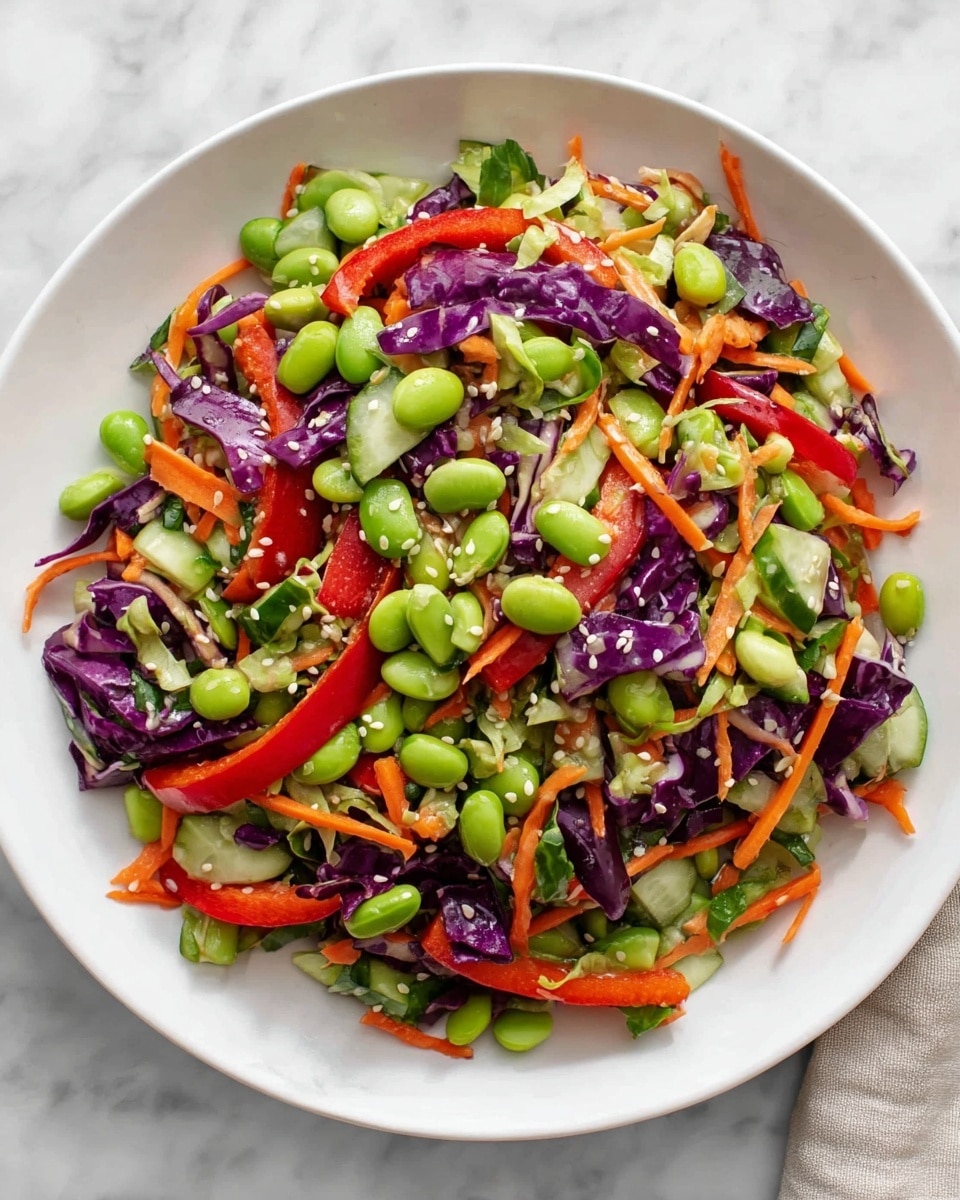A white plate filled with a colorful mixed salad on a white marbled surface, showing different layers of fresh vegetables. The bottom layer is mainly bright green edamame beans scattered evenly. Above that, there are thin strips of orange carrot spread all around. There are also shiny red bell pepper pieces and dark purple cabbage leaves with white veins mixed through. Small chunks of green cucumber add extra texture. White sesame seeds are sprinkled on top, adding small white dots. The salad looks fresh and lively with a mix of crunchy textures and vibrant colors. Photo taken with an iphone --ar 4:5 --v 7