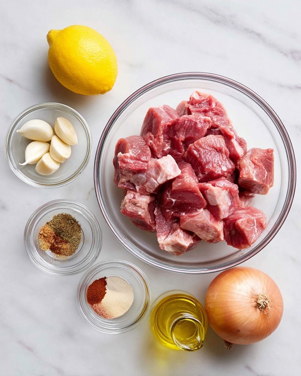 The image shows a set of ingredients arranged on a white marbled surface. In the center, a clear glass bowl holds raw meat pieces in red and pink shades with some white fat. To the left, a bright yellow lemon and a small glass bowl containing three garlic cloves are placed. Below them, another small glass bowl contains a mix of spices in brown, red, and beige colors. To the right of the meat bowl, there is a whole onion with a yellow-brown skin, and below it, a small clear glass bottle filled with golden olive oil. All items are neatly placed, creating a clean and organized look. Photo taken with an iphone --ar 4:5 --v 7