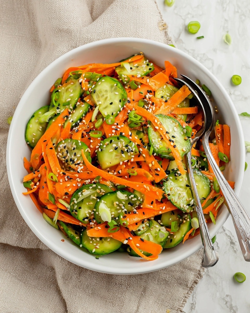 A white bowl filled with a fresh salad showing two main layers: bright orange thin carrot sticks on top and light green cucumber slices mixed throughout. Scattered on top are small green onion slices and both black and white sesame seeds, adding texture and color contrast. Two silver forks are placed inside the bowl on the right side. The bowl rests on a beige cloth with green onion slices and sesame seeds around it on a white marbled surface. Photo taken with an iphone --ar 4:5 --v 7