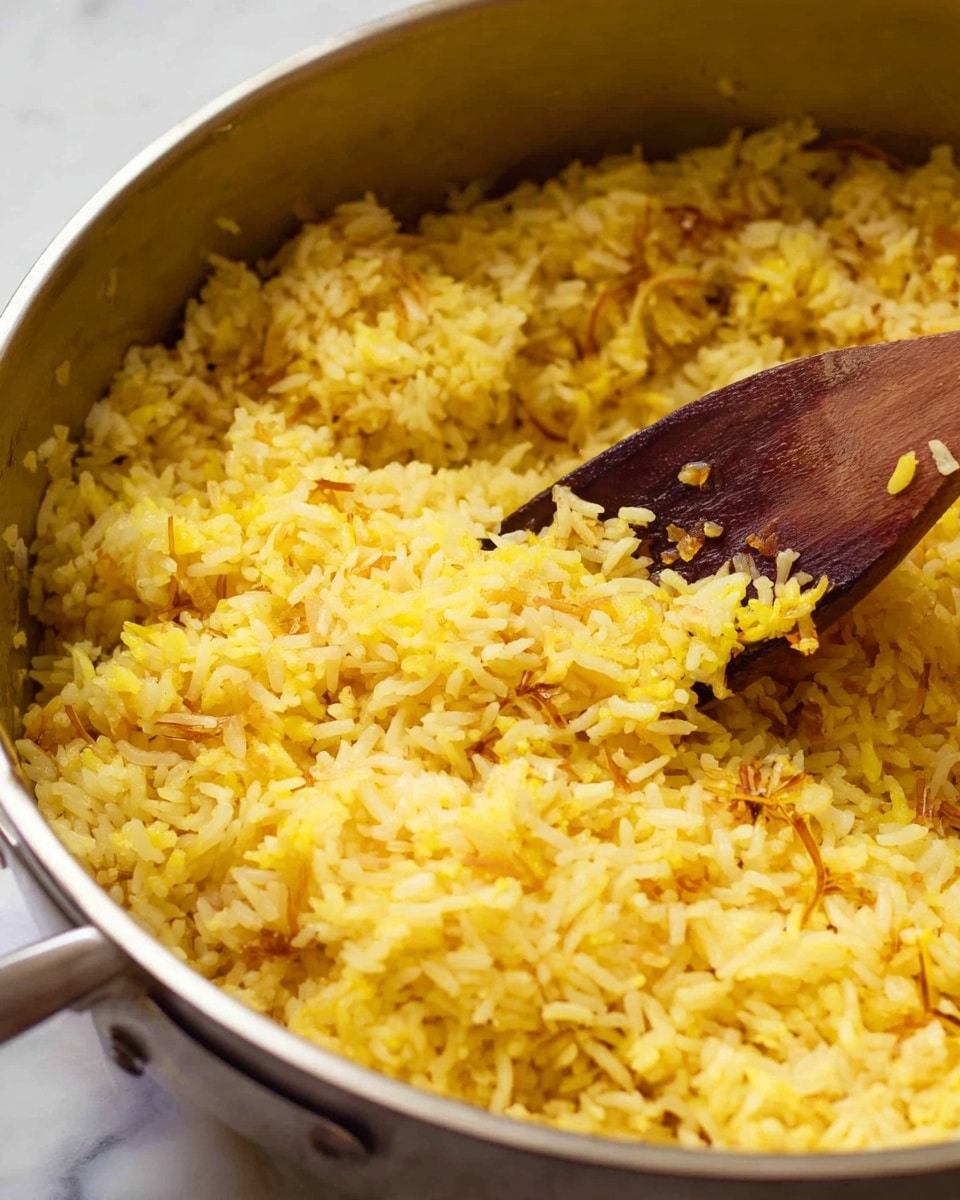 A close-up view of cooked yellow rice in a silver pot, with a wooden spoon stirring the rice. The rice grains are fluffy and separated, with a light yellow color and small browned bits showing a slight toasted texture. The wooden spoon has some grains of rice on it, with a smooth, dark brown top and lighter wooden handle. The background is a white marbled texture. photo taken with an iphone --ar 4:5 --v 7