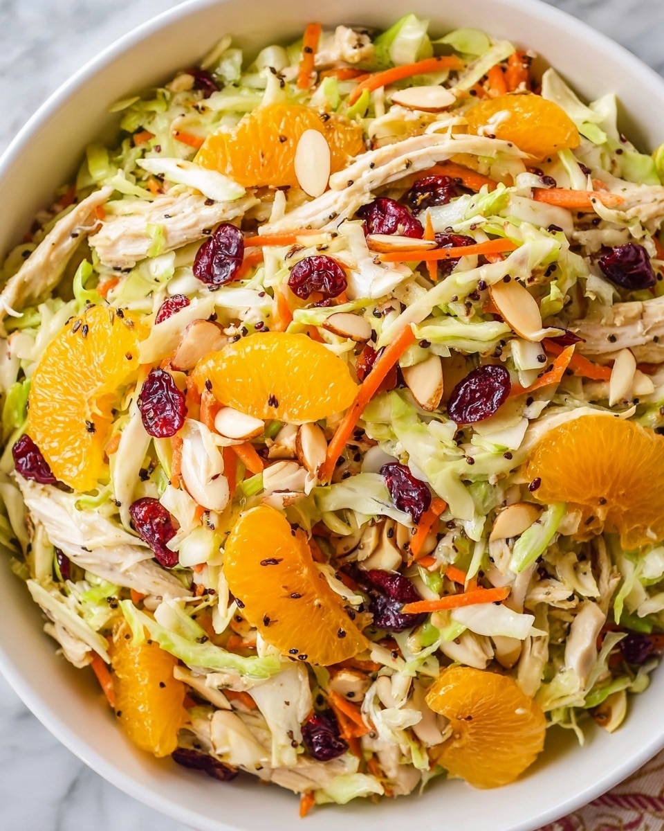A white bowl filled with a colorful salad made of shredded light green cabbage, thin orange carrot strips, and pale shredded chicken mixed evenly. Bright orange mandarin slices are spread throughout, along with scattered small red dried cranberries and pale almond slices. Tiny black seeds are sprinkled on top, adding a bit of texture. The bowl rests on a white marbled surface. Photo taken with an iphone --ar 4:5 --v 7