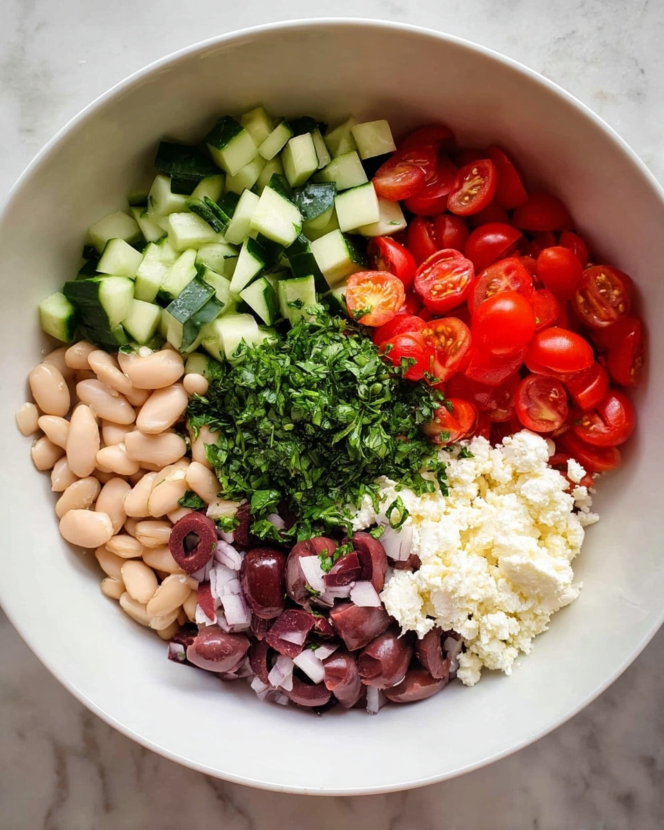 A white bowl filled with six separate layers of fresh ingredients displayed in a circular form. Starting at the top, there are small green cubes of cucumber with a smooth texture, moving clockwise to finely chopped dark purple olives, then bright red halved cherry tomatoes with seeds visible inside. Below the tomatoes, there are white beans with a soft texture. On the left side, there is a layer of crumbly white cheese, and finally, in the center, a pile of finely chopped fresh green herbs. The bowl is set on a white marbled surface. photo taken with an iphone --ar 4:5 --v 7