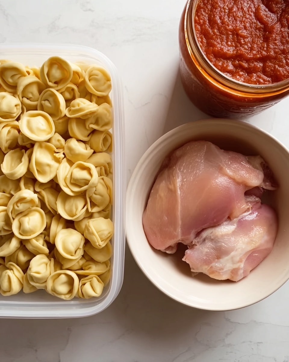 The image shows a white plastic container on the left filled with small, round, pale yellow tortellini pasta. On the right, there is a white bowl holding two raw pinkish pieces of chicken skin. Above the bowl, part of a red jar with a thick tomato-based sauce is visible. All items are placed on a white marbled surface. photo taken with an iphone --ar 4:5 --v 7