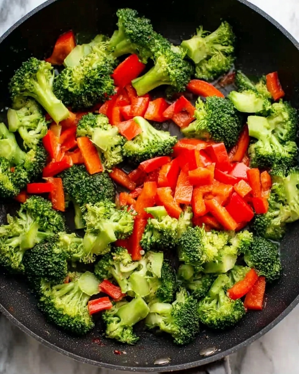 The image shows a black pan filled with bright green broccoli florets and pieces of red bell pepper. The broccoli pieces are chunky, some with visible stalks, and are spread evenly around the pan. The red bell pepper pieces are medium-sized, smooth, and vibrant, scattered over the broccoli, creating a contrast of green and red colors. The background is a white marbled texture. photo taken with an iphone --ar 4:5 --v 7