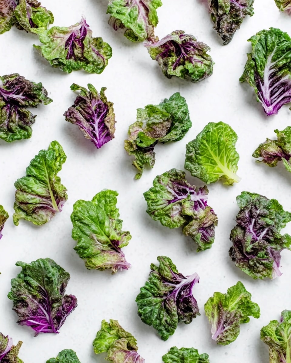 The image shows many small pieces of leafy greens scattered evenly across a white marbled surface. Each piece has a mix of green and purple colors, with ruffled edges and some light texture variations, showing natural veins on the leaves. There is no plate or bowl, only the scattered leaves against the smooth, light background. The leaves vary in size and shape but keep a consistent fresh and vibrant look. photo taken with an iphone --ar 4:5 --v 7
