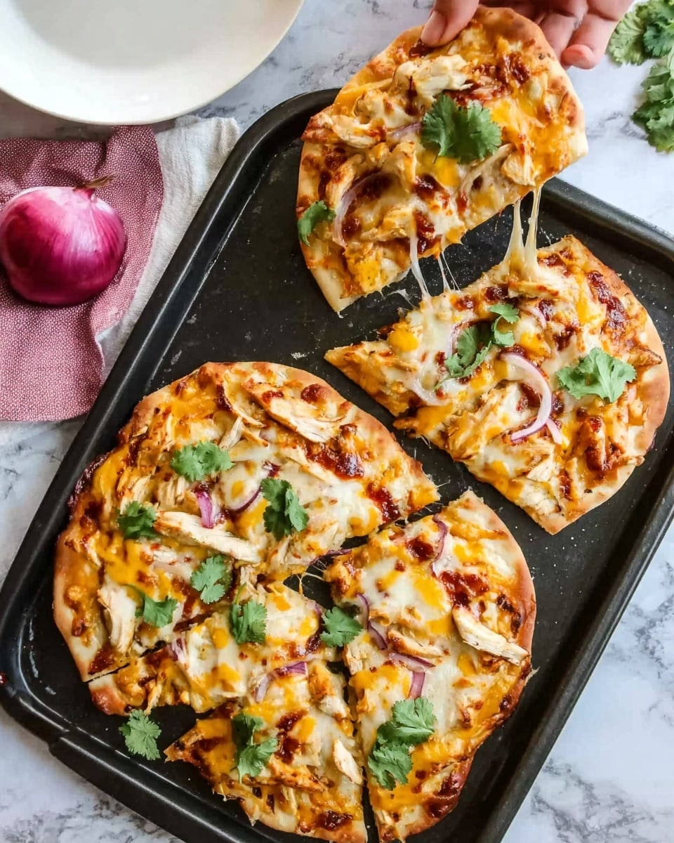 The image shows a black baking tray on a white marbled surface with two small round pizzas on it. One pizza is whole, topped with melted yellow and white cheese, orange sauce, chopped light-colored grilled chicken, and fresh green cilantro leaves. The other pizza has two slices removed and a woman's hand holding a slice above the tray, showing gooey melted cheese stretching. The pizzas have crispy golden edges and a thin crust. A red onion and a white plate with a pink and white cloth are visible in the background. Photo taken with an iphone --ar 4:5 --v 7