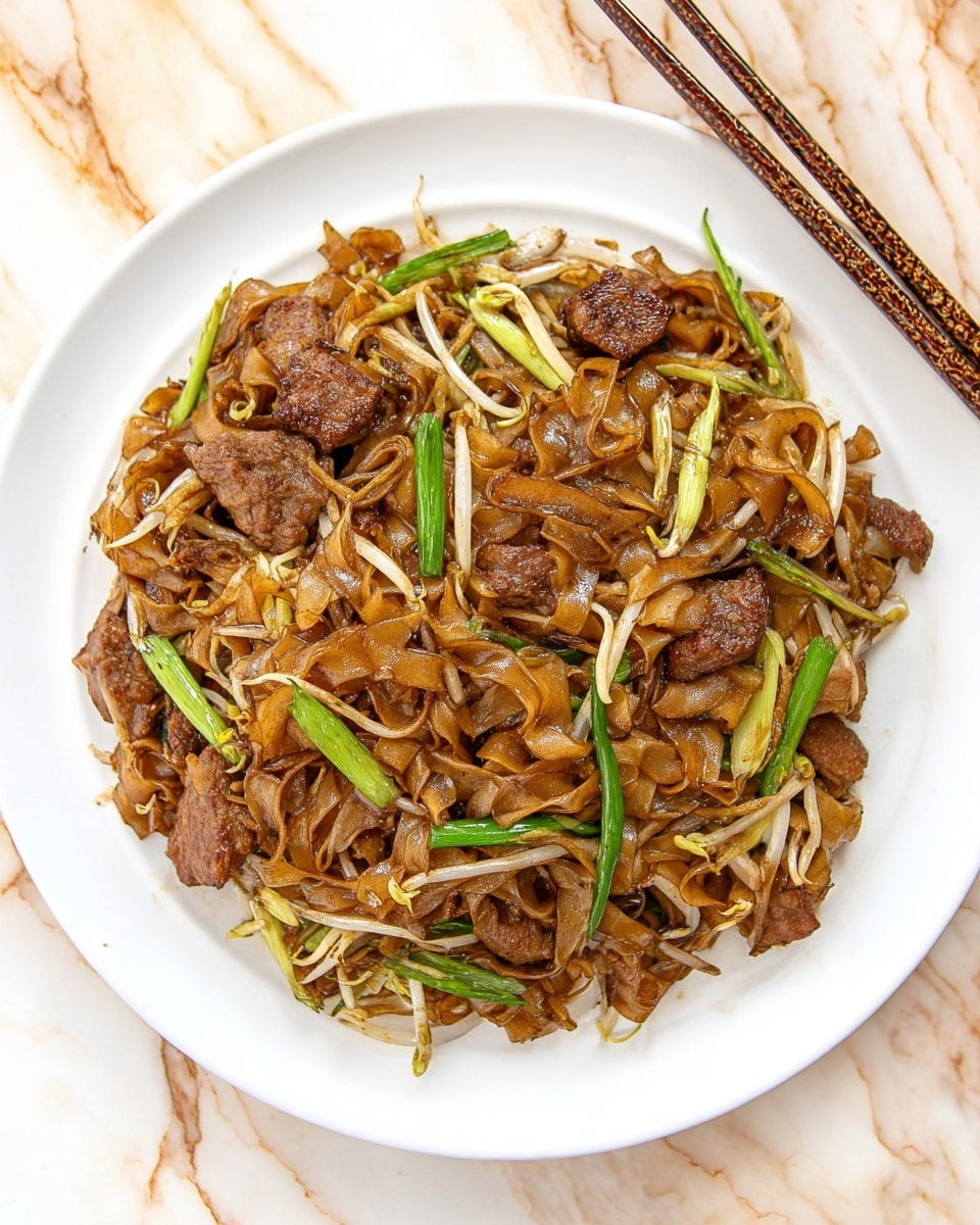 The dish shows a white round plate filled with dark brown, shiny stir-fried flat noodles mixed with green spring onions, light brown bean sprouts, and pieces of cooked meat with a slightly crispy texture. The noodles have a glossy look and uneven edges with some onions scattered throughout that add light yellow and green colors. The plate sits on a white marbled surface with wooden chopsticks resting on the top right edge. photo taken with an iphone --ar 4:5 --v 7