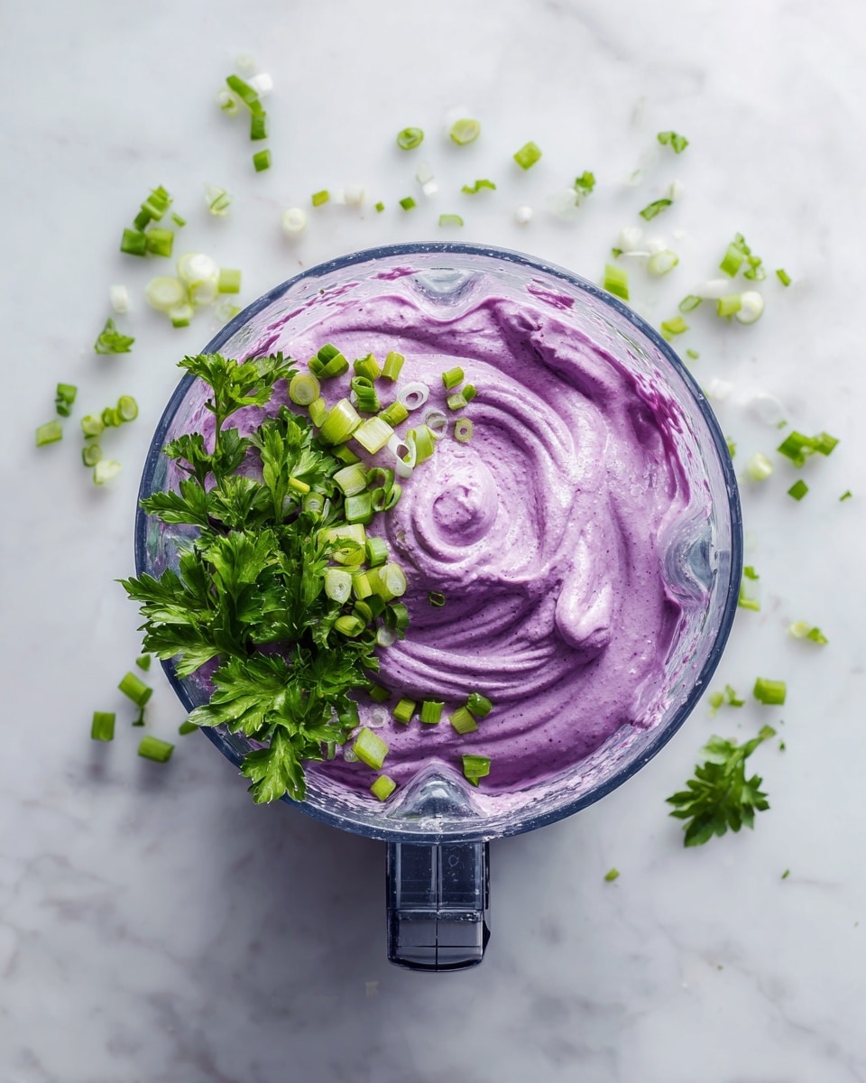 A blender container filled with a bright purple creamy spread that has a smooth and swirled texture, topped with fresh green parsley and chopped green onions scattered on one side, all placed on a white marbled surface, captured from a top-down view. Photo taken with an iphone --ar 4:5 --v 7