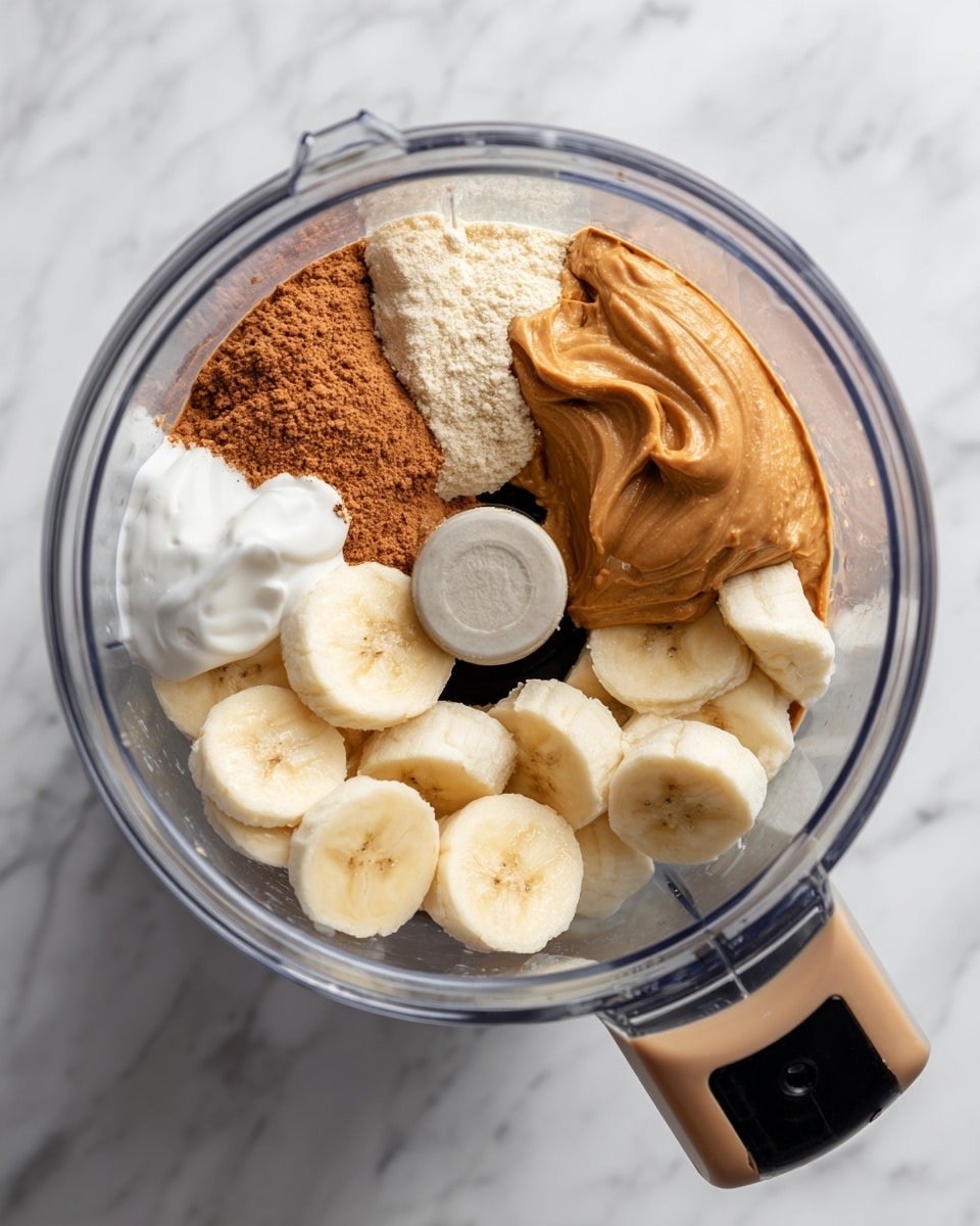 The image shows the inside of a clear blender bowl on a white marbled surface. Inside the bowl, there are four main layers: light tan powder on one side, thick brown peanut butter on the right side, small white yogurt on the lower right side, and sliced banana pieces scattered on the lower left side. The blender blade is visible in the center below the ingredients. The blender lid has a black handle with a tan loop attached on the side. photo taken with an iphone --ar 4:5 --v 7
