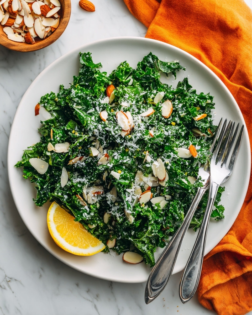 A fresh salad with bright green kale leaves as the main layer, topped with white almond slices scattered evenly, and sprinkled with finely grated white cheese that covers the leaves lightly. There is a wedge of yellow lemon positioned on the bottom right edge of the white plate. Two shiny metal forks are placed inside the salad, with their handles pointing upwards. The plate is set on a white marbled surface, with a small bowl of more almond slices in the upper left corner and an orange cloth roughly folded in the lower left corner. Photo taken with an iphone --ar 4:5 --v 7