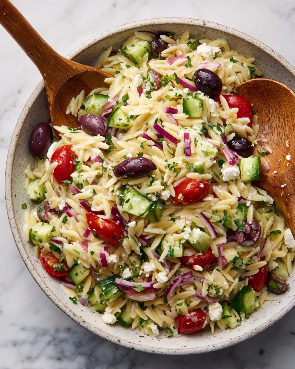 The image shows a colorful salad with three main layers mixed together: a base of pale, creamy orzo pasta grains, a middle layer of bright green cucumber chunks and deep red grape tomato halves, and a top layer of scattered dark purple olive slices, small bits of red onion, white crumbles of cheese, and finely chopped green herbs. Two wooden spoons are partially visible, mingling the ingredients. The salad rests on a white marbled textured surface. photo taken with an iphone --ar 4:5 --v 7