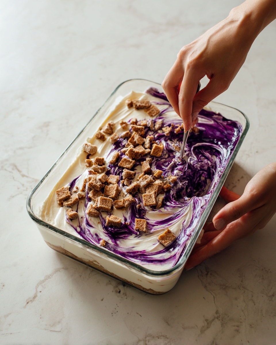 The image shows a clear rectangular glass dish with three visible layers of a dessert. The bottom layer is creamy white, covering the entire base. On top of that is a dark purple layer, spread unevenly in the middle and towards the edges, creating a swirled effect. The top layer consists of many small, square, brown pieces scattered over the purple part. A woman’s hand is holding the dish on the left side, while another woman’s hand on the right is stirring or mixing the layers, making the white and purple colors blend a little. The dish is placed on a white marbled surface. photo taken with an iphone --ar 4:5 --v 7