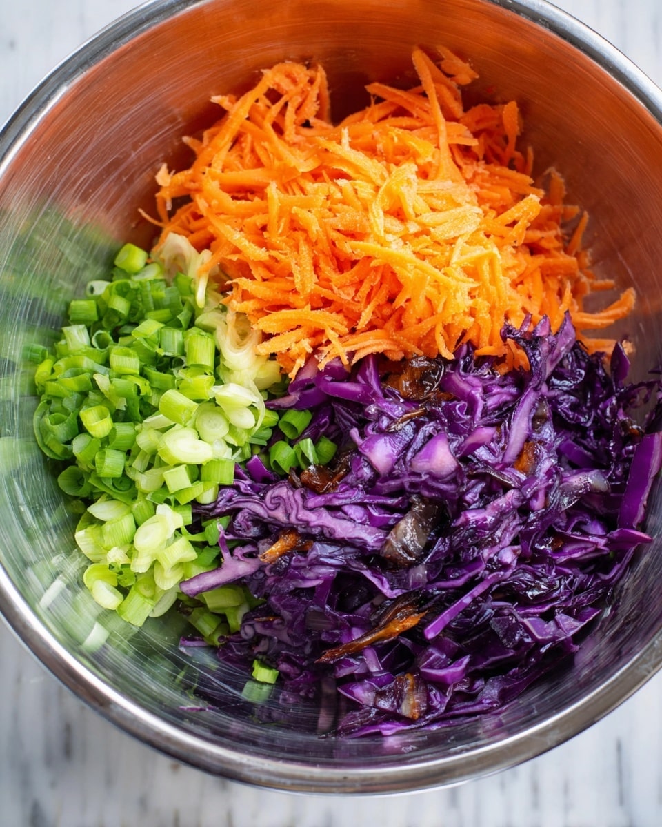 A clear glass bowl sitting on a white marbled surface contains three distinct layers of vegetables. On the top left is a bright orange layer of shredded carrots with a slightly rough texture. To the bottom left, there is a fresh green layer of chopped green onions with a crisp look. On the right side, occupying more than half of the bowl, is a purple layer of cooked or sautéed cabbage with some darker charred spots. The shiny surface of the glass bowl reflects light, adding brightness to the vibrant colors of the vegetables. Photo taken with an iphone --ar 4:5 --v 7
