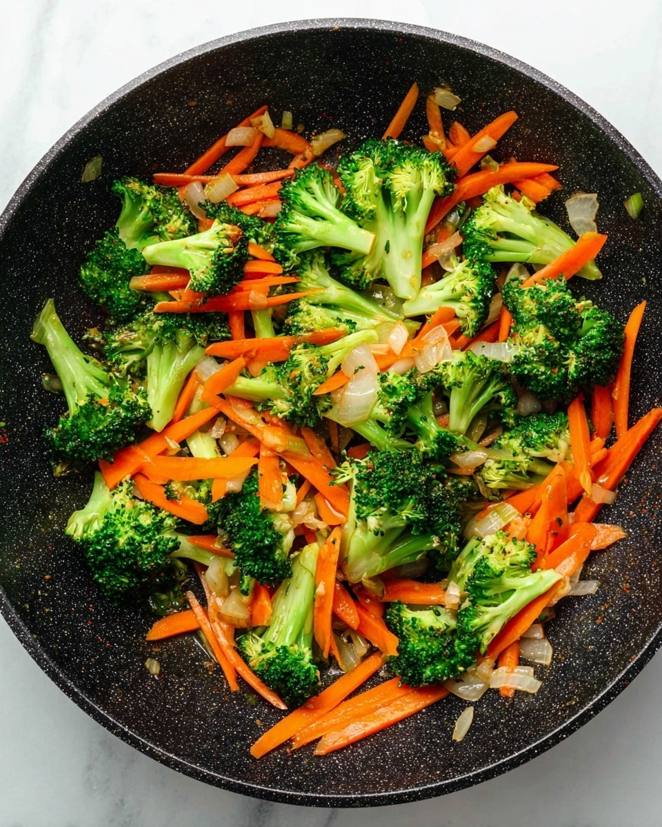 A round black frying pan holds a colorful mix of vegetables, with bright green broccoli florets scattered throughout and thin, long strips of orange carrots spread evenly underneath and around the broccoli. Small pieces of white onion bits are mixed lightly in with the vegetables. The inside of the pan has a speckled texture that contrasts with the fresh, vibrant vegetables. The pan is placed on a white marbled surface. photo taken with an iphone --ar 4:5 --v 7