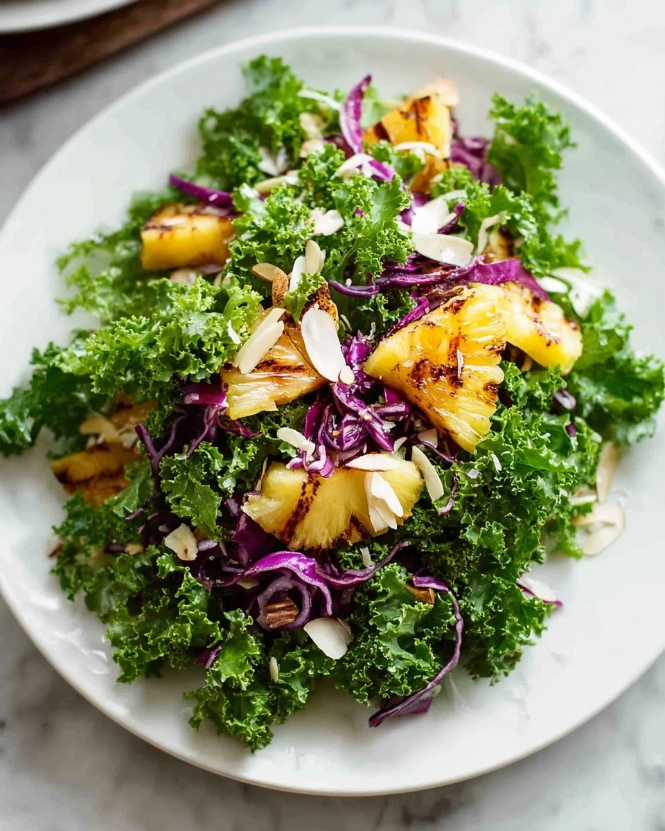 A white plate holds a fresh salad with three main layers: the base is made of bright green curly kale leaves, adding a textured, leafy look; scattered on top are small, grilled pineapple chunks with light brown grill marks, giving a soft golden yellow and caramelized texture; mixed throughout are thin, purple-red strips of cabbage adding a splash of vibrant color, and thin white slivers of almonds add a mild roughness and crunchy texture. The plate sits on a white marbled surface. photo taken with an iphone --ar 4:5 --v 7