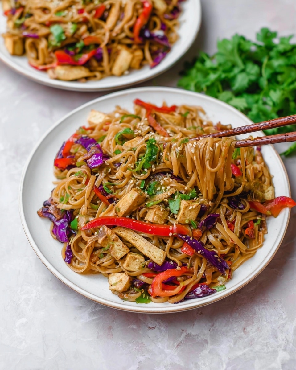 Two white plates filled with stir-fried noodles sit on a white marbled surface. Each plate has three main layers: at the bottom, a bed of light brown noodles with a soft, slightly glossy texture; the middle layer includes colorful vegetable strips such as bright red bell peppers and purple cabbage, adding pops of red and purple; the top layer features small green cilantro leaves and light beige tofu strips mixed evenly, along with some sprinkled sesame seeds. One plate is shown with wooden chopsticks lifting a portion of noodles, while fresh green cilantro lies beside the plates. photo taken with an iphone --ar 4:5 --v 7