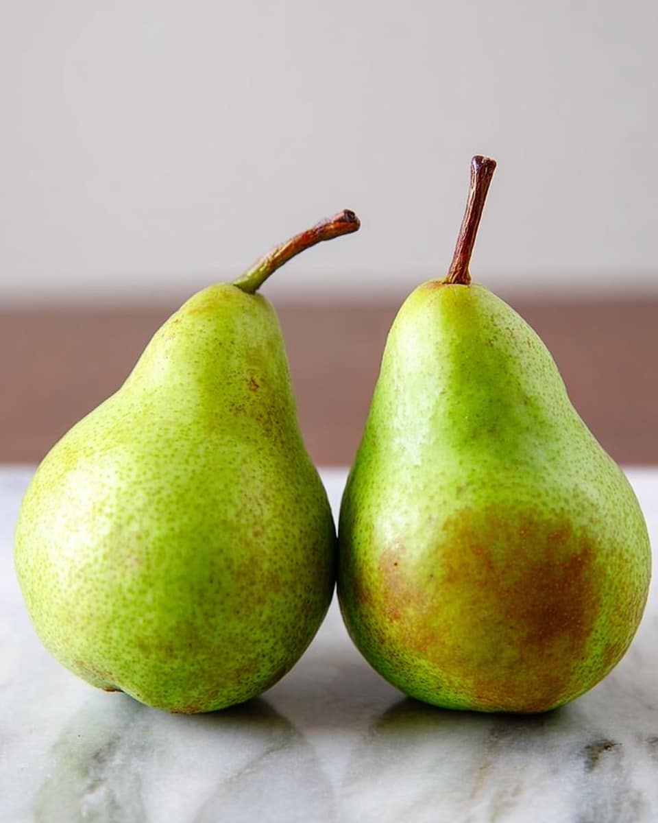 Two whole green pears stand side by side on a white marbled surface. Each pear has a smooth skin with a mix of light green shades and soft brownish patches near the bottom. Both have a short brown stem at the top, and the pears are close enough to slightly lean toward each other. The background is plain and light, making the pears the main focus. Photo taken with an iphone --ar 4:5 --v 7