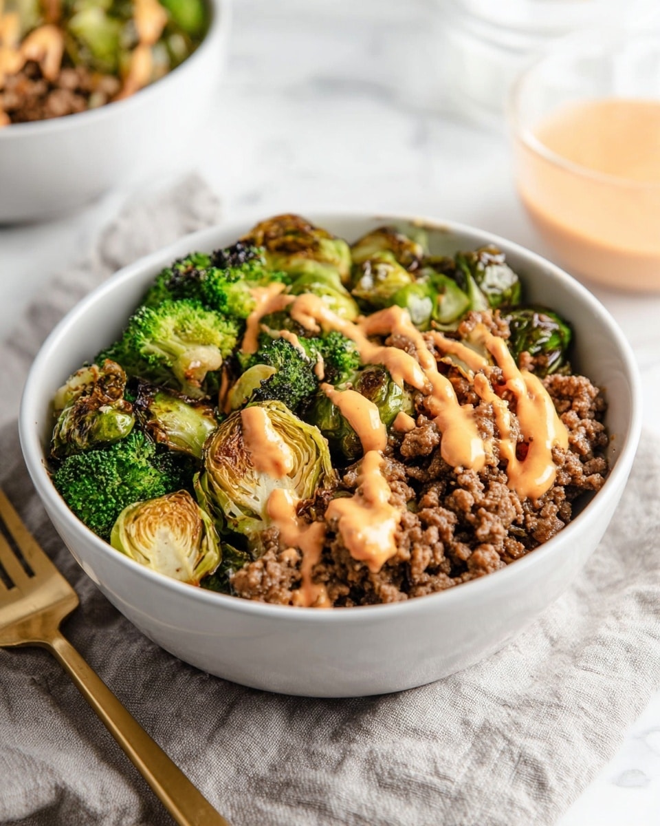 A white bowl filled with a layered mix of cooked vegetables and ground meat. At the bottom, there are bright green roasted Brussels sprouts and broccoli with a slight charred texture. On top of the vegetables, there is a generous layer of crumbly brown ground meat. Scattered among the meat are small pieces of red tomato adding a pop of color. Drizzled over the top is a smooth, light orange sauce in thin lines. The bowl is placed on a white marbled surface, with another similar bowl blurred in the background and an orange drink visible in the upper right corner. Photo taken with an iphone --ar 4:5 --v 7
