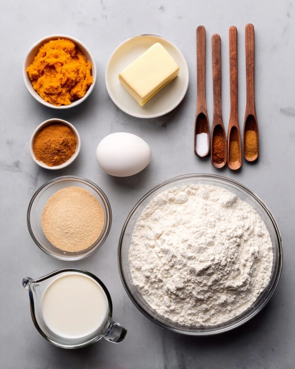 The image shows ingredients for baking arranged neatly on a white marbled surface. On the right side, there is a large clear bowl filled with white flour. To the left of the flour, there is a small white bowl with a light yellow stick of butter, and next to it is a white egg. Below these, there is a small clear bowl with light beige yeast and another clear bowl with brown cinnamon. At the bottom left, a measuring cup holds a white liquid, likely milk. Above it, there is a set of four wooden measuring spoons containing different spices and ingredients: one with orange pumpkin puree, one with white sugar, one with salt, and the smallest with a brown spice. The colors are mostly white, orange, beige, and brown, and the arrangement is simple and orderly. photo taken with an iphone --ar 4:5 --v 7