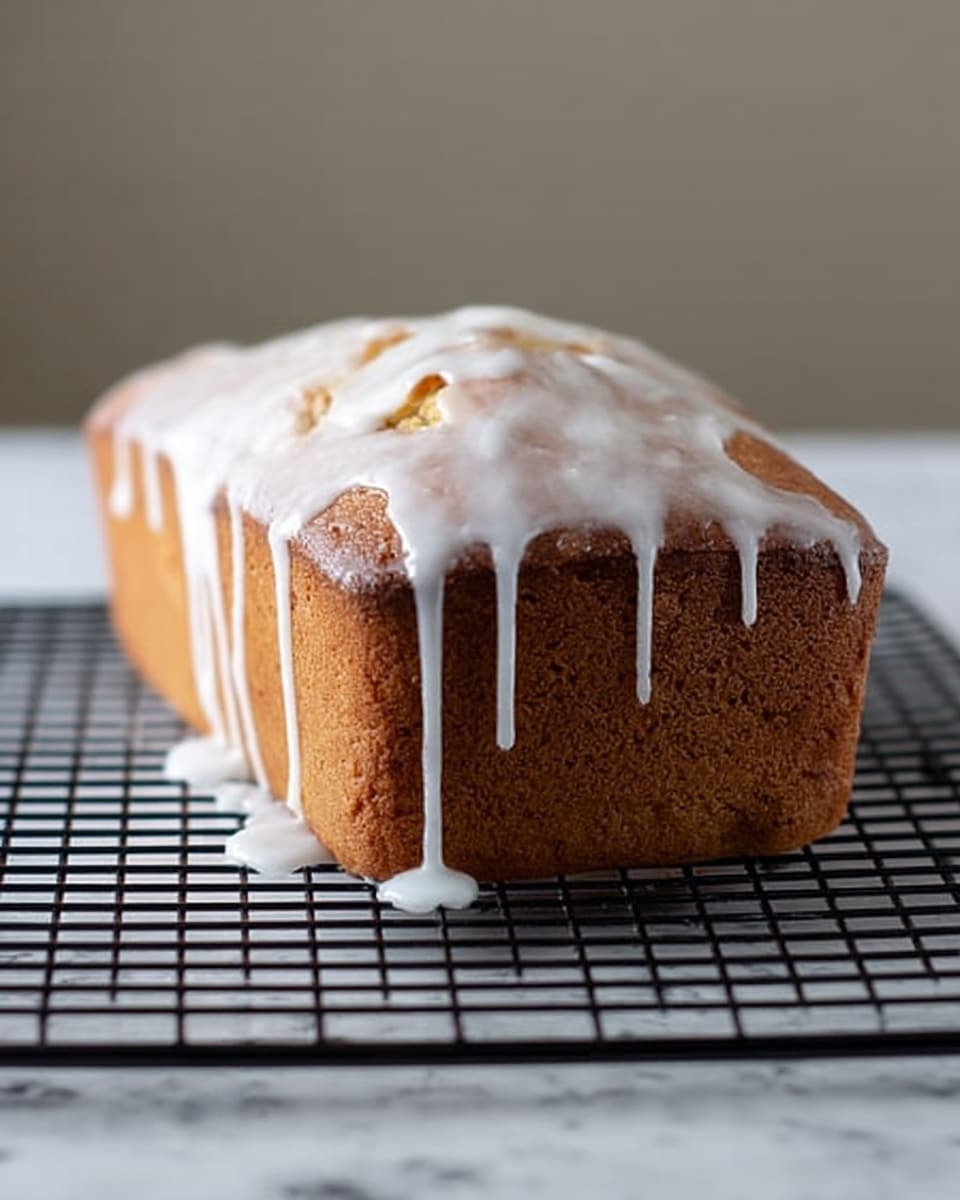 A single loaf cake sits on a black cooling rack, placed on a white marbled surface. The cake has one main layer with a golden brown color and a slightly uneven top. A thick white glaze is poured over the top, dripping down in long streaks on one side. The texture of the cake looks soft but firm, with small visible pieces inside the batter. The background is soft and blurred, focusing attention on the cake. Photo taken with an iphone --ar 4:5 --v 7