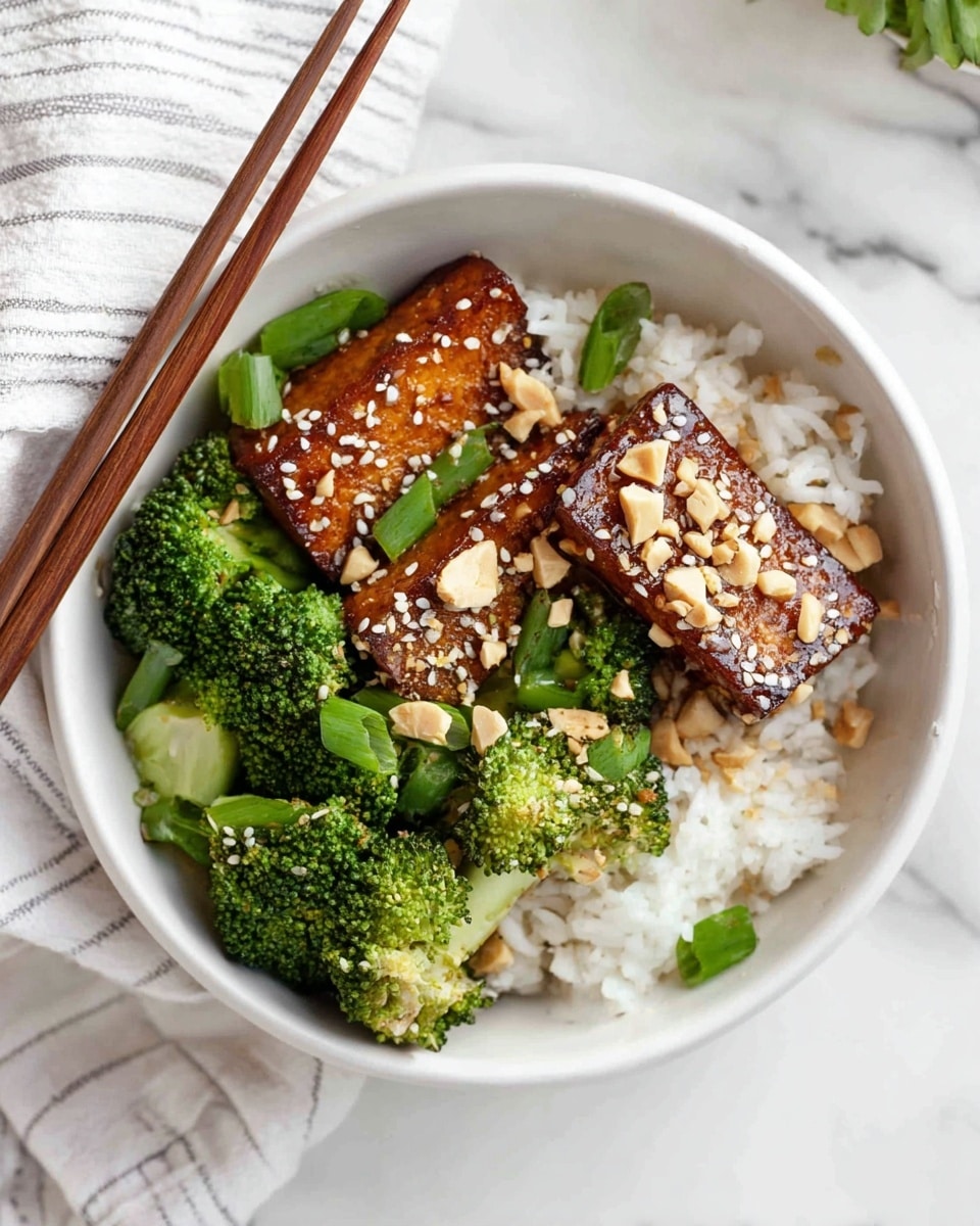 The image shows a white bowl with three layers: the bottom layer is white cooked rice, the middle layer contains bright green broccoli florets, and the top layer has three pieces of brown glazed tofu sprinkled with white sesame seeds and crushed peanuts. There are a few green onion slices scattered over the tofu and rice. A pair of wooden chopsticks rests on the left side of the bowl. The background is a white marbled surface with a white and gray striped cloth partially visible on the left side. Photo taken with an iphone --ar 4:5 --v 7