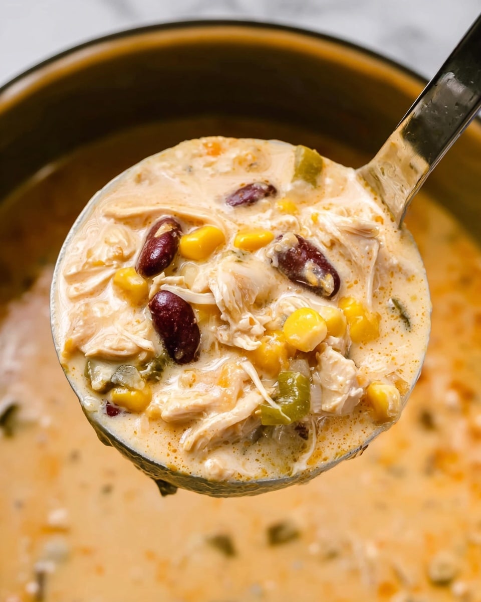A close-up of a ladle full of creamy soup with layers visible: a thick, light orange creamy broth mixed with shredded white chicken pieces, whole yellow corn kernels, dark red kidney beans, and small chunks of green bell pepper. The ladle is held above a larger pot filled with the same soup, all set against a white marbled surface. The thick texture and colorful ingredients create a rich, hearty look. photo taken with an iphone --ar 4:5 --v 7
