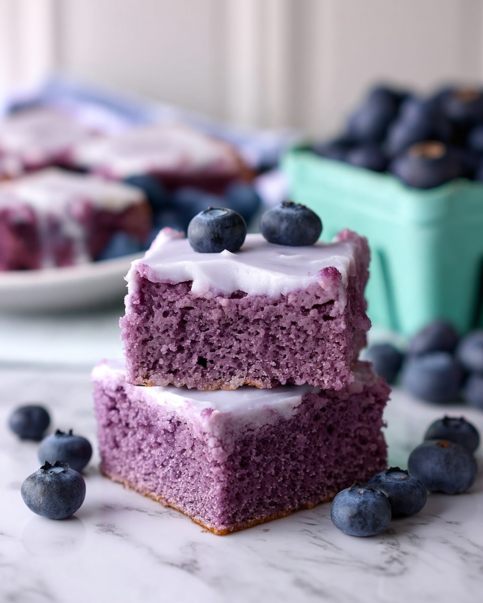 The image shows two square slices of purple cake stacked on top of each other, each with a smooth light purple frosting layer on top. The texture of the cake is moist and dense with small holes visible, and the frosting looks creamy and slightly shiny. Around the cakes are fresh dark blue blueberries scattered on a white marbled surface. In the background, there is a white plate with more cake slices and a light blue-green container filled with blueberries, all slightly blurred. Photo taken with an iphone --ar 4:5 --v 7
