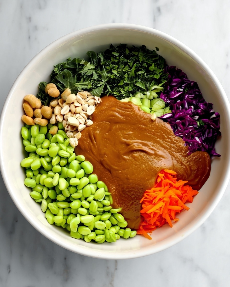 A white bowl on a white marbled surface holds a colorful salad with seven distinct layers. Starting from the bottom left and moving clockwise, there is a large pile of bright green edamame beans with a smooth texture, followed by light brown peanuts with a slightly rough texture. Next, there are dark green kale leaves with a crinkled texture, finely chopped cilantro with a fresh green color, thin light green slices of celery, and finely shredded purple cabbage. In the center, there is a thick layer of smooth brown peanut sauce spreading over part of the other ingredients, next to a pile of bright orange shredded carrots. The layers are neatly separated and vivid. Photo taken with an iphone --ar 4:5 --v 7