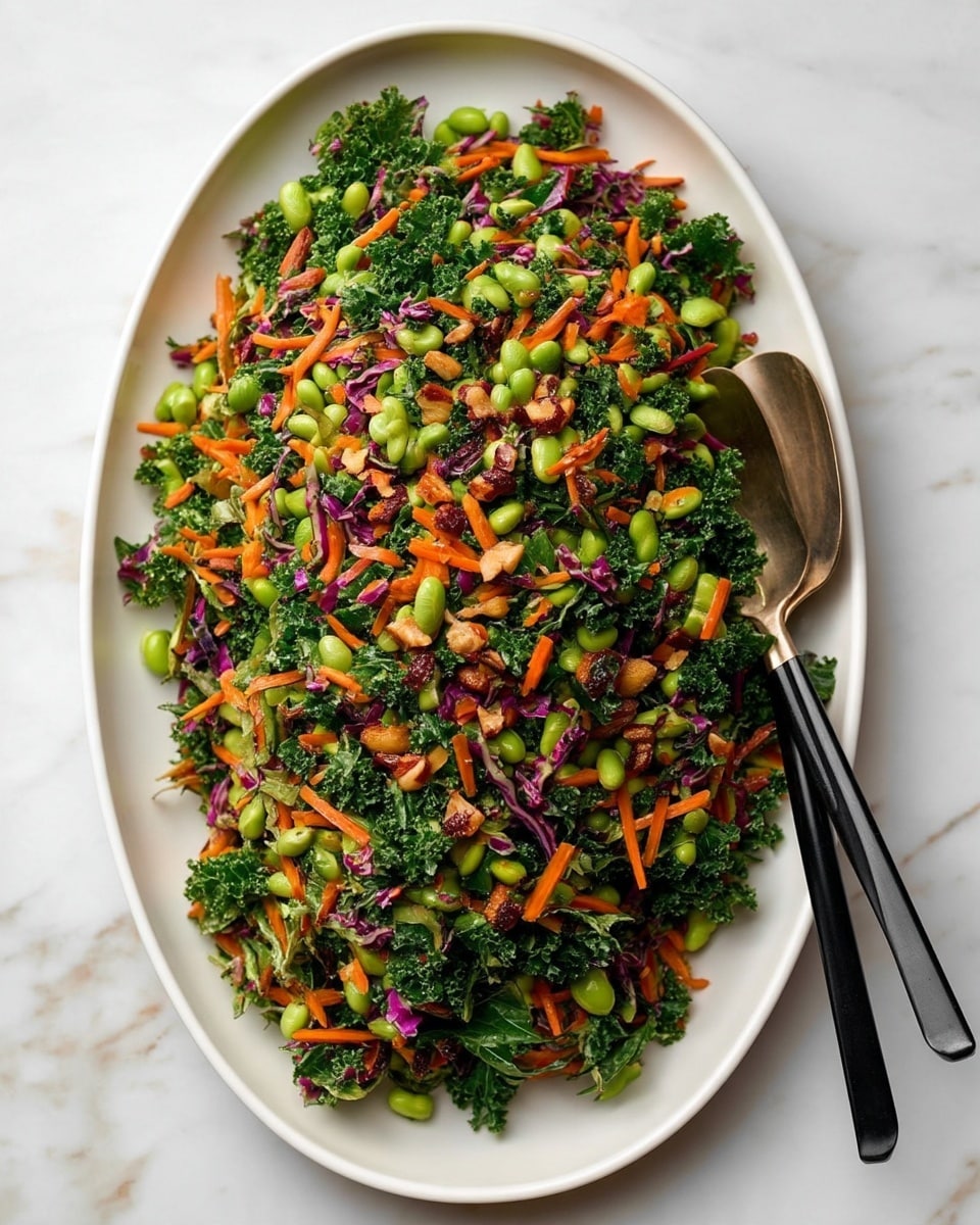 A large white oval plate is filled with a colorful salad made of several layers, the bottom layer is shredded green kale and purple cabbage, mixed evenly. Scattered over this base are bright orange thin carrot strips and light green edamame beans, adding texture and color contrast. Small pieces of chopped nuts are spread throughout the salad, visible on the top. On the right side of the plate, two black-handled utensils rest on the edge, partially buried under the salad. The plate sits on a white marbled surface that softly reflects light. photo taken with an iphone --ar 4:5 --v 7