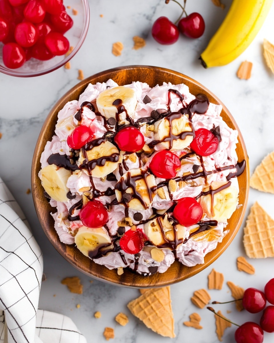 A round wooden bowl sits on a white marbled surface filled with a creamy pink dessert that has a soft, fluffy texture. On top, there are thick slices of yellow banana and bright red cherries scattered evenly. Dark brown chocolate sauce is drizzled across the top in a loose crisscross pattern, and there are small chunks of light brown nuts sprinkled throughout. Around the bowl, pieces of broken light tan waffle cones are visible. In the top left corner, a clear bowl holds more red cherries, and a white cloth with black stripes is partially visible at the bottom left corner. Photo taken with an iphone --ar 4:5 --v 7